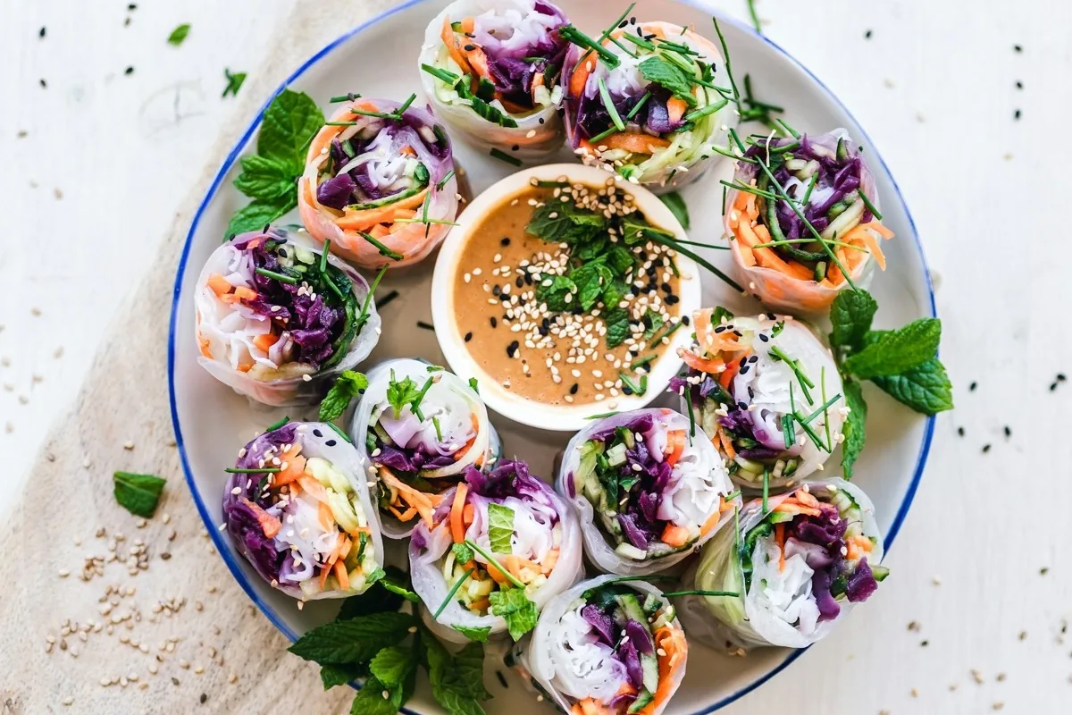 Frische Sommerrollen mit buntem Gemuese und Erdnuss-Dip auf einem Teller